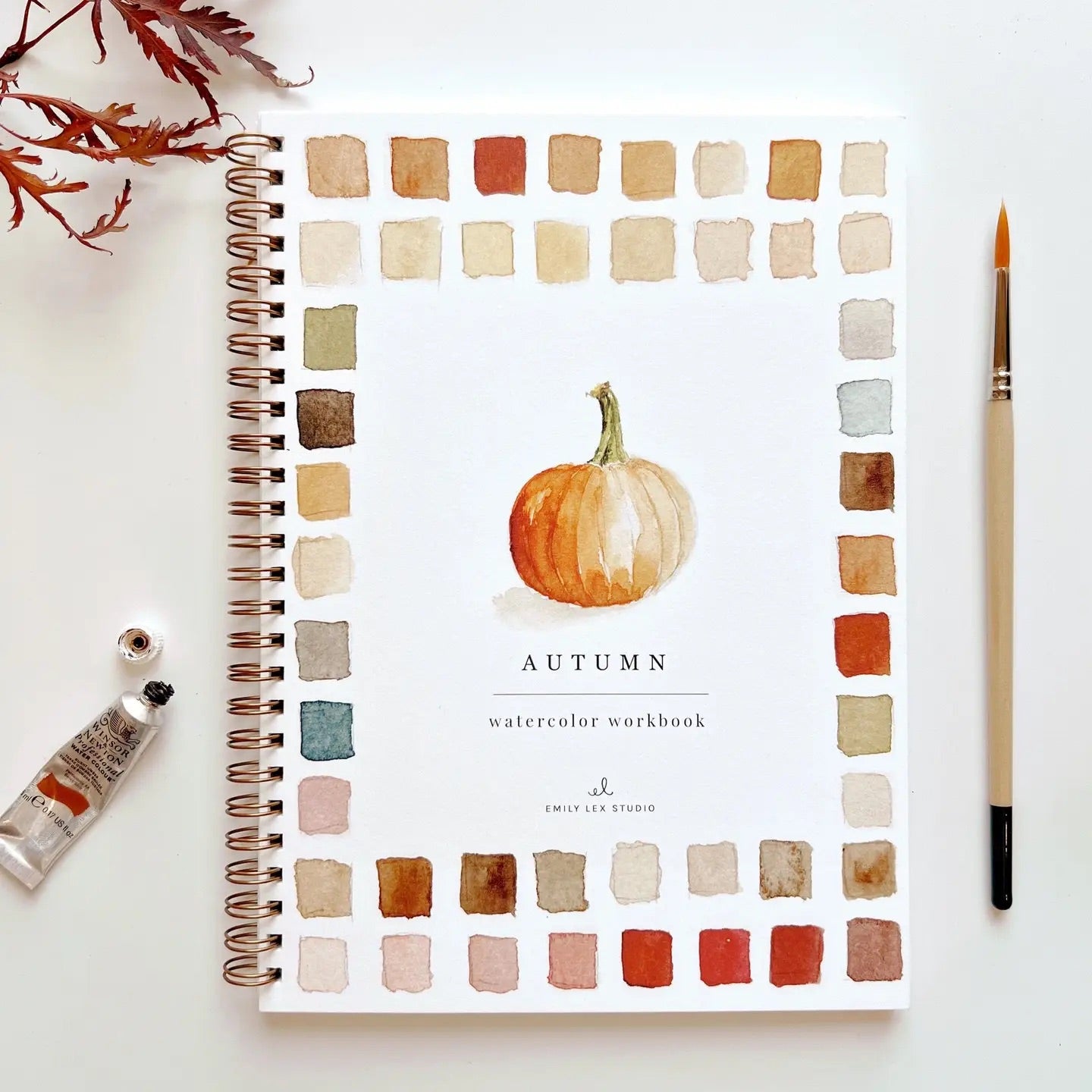 Spiral-bound watercolor workbook with pumpkin painting on the cover. Black text reads "autumn watercolor workbook."