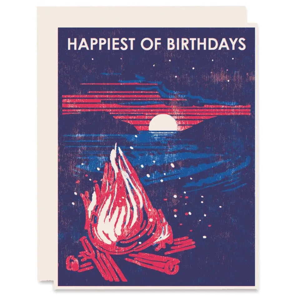 White greeting card with full color blue background. Pink, purple, blue, and white illustration of a beach bonfire. White text "happiest of birthdays"