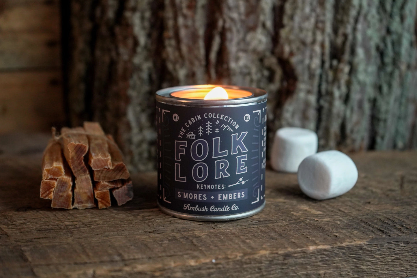 Folklore candle with wooden logs and marshmallows on a rustic background