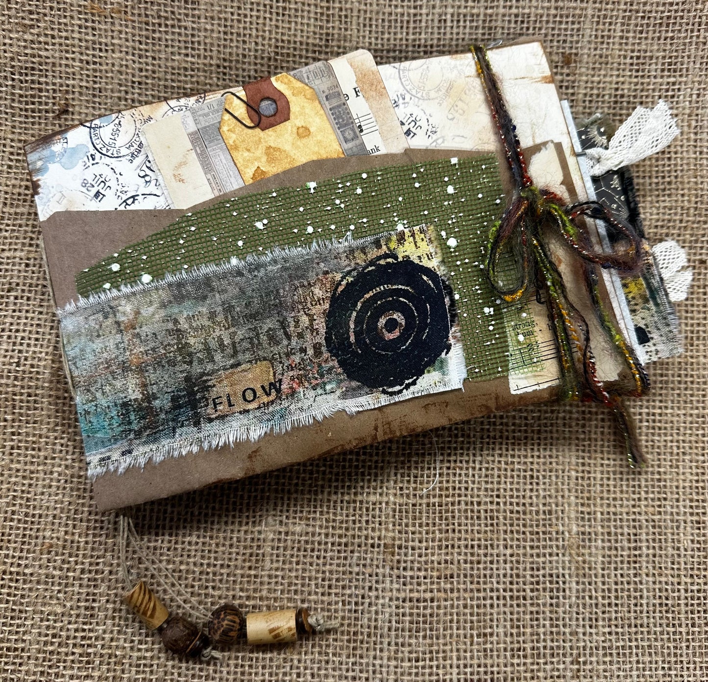 Handmade journal with textured surface and decorative elements on a burlap background