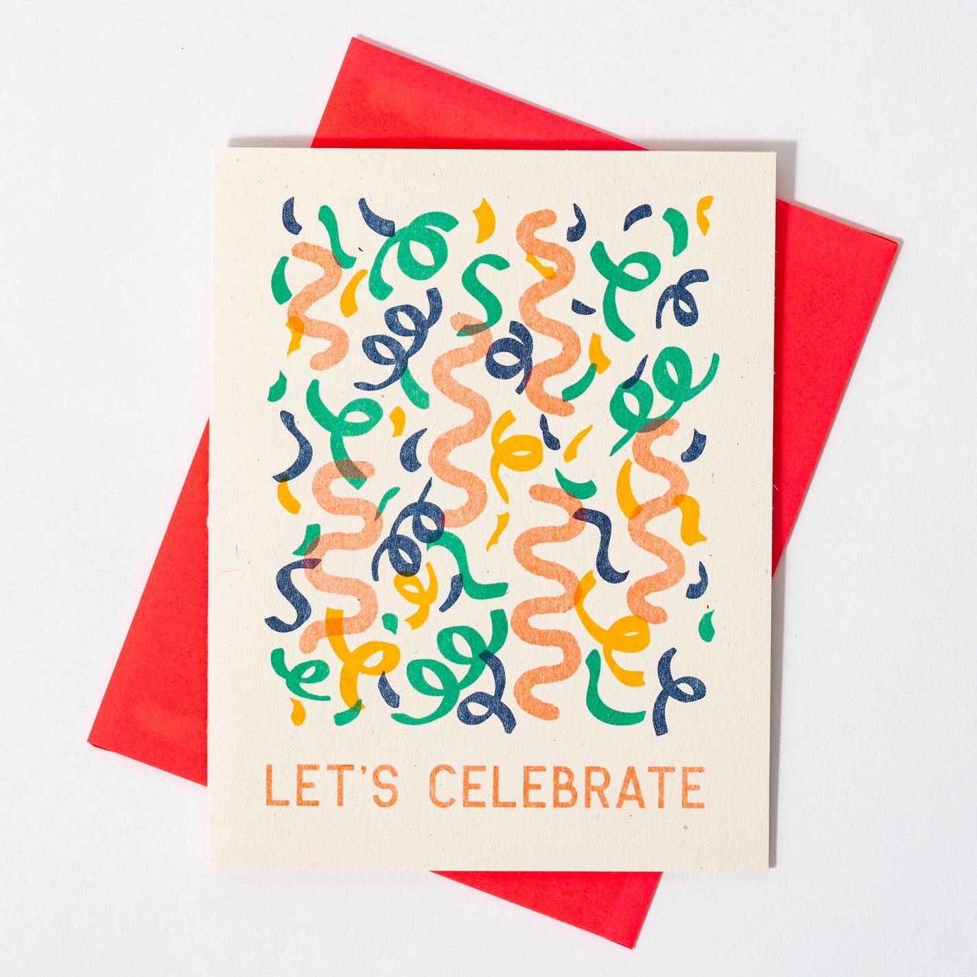 Cream colored greeting card with multicolor streamers printed on it. Orange text "let's celebrate"