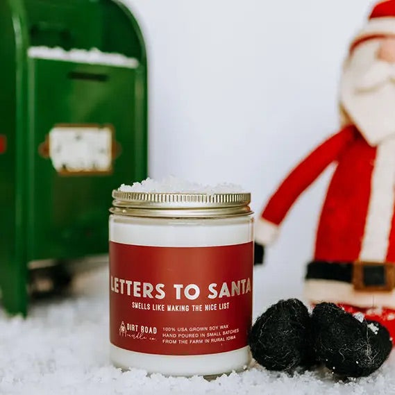 Clear jar filled with white candle. Red label with silver text “letters to Santa”