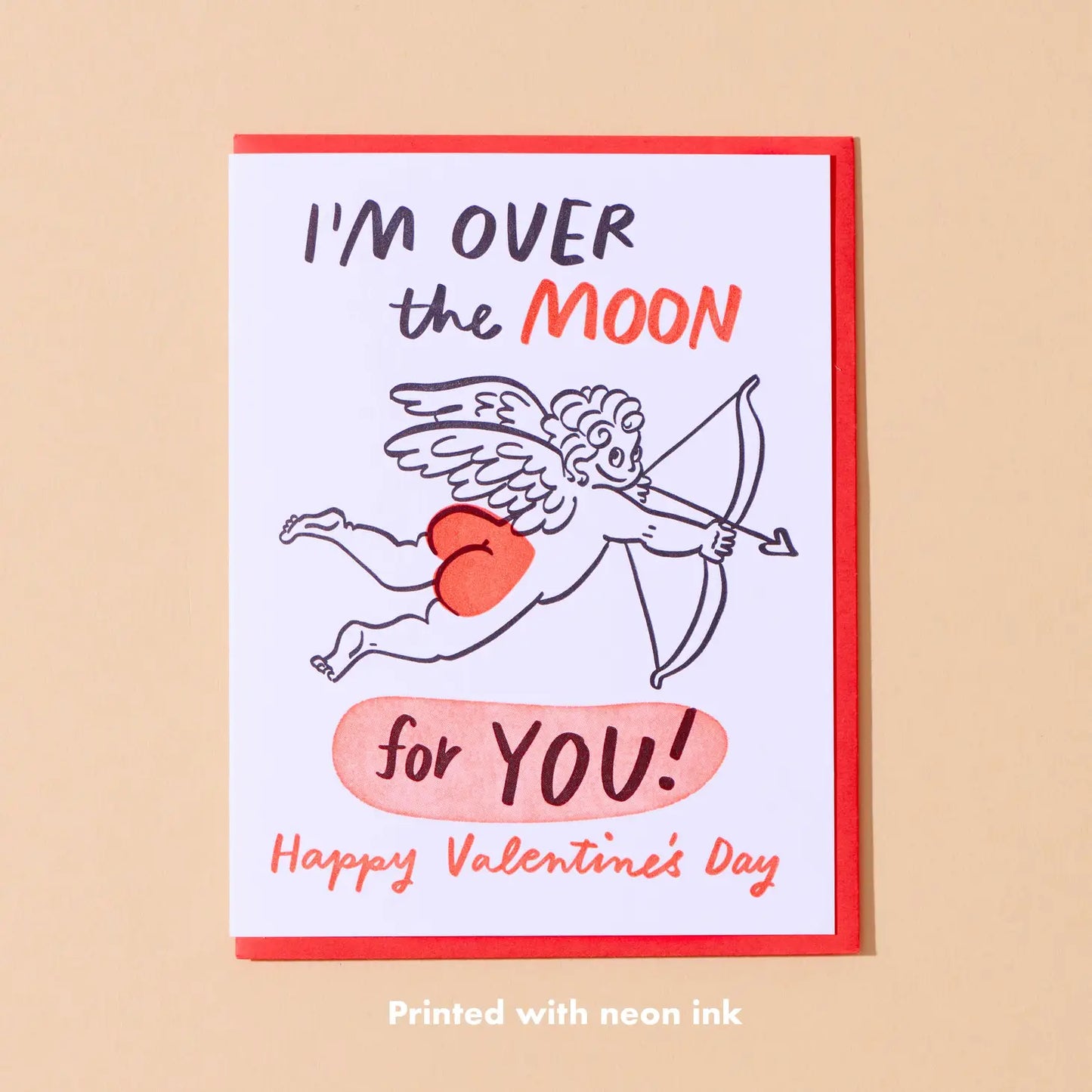 White card with a black and white illustration of a cupid holding a bow and arrow. Filled red heart on cupid's butt. Black and red text reads "I'm over the moon for you! Happy Valentine's Day"
