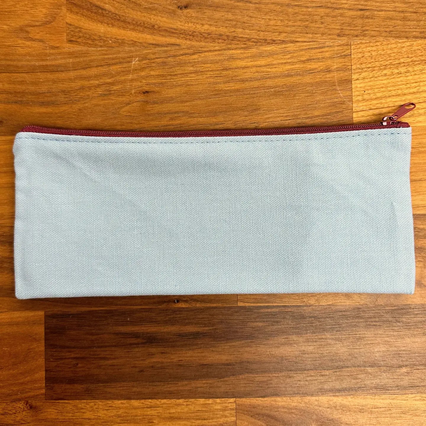 Light blue zipper pouch on a wooden surface