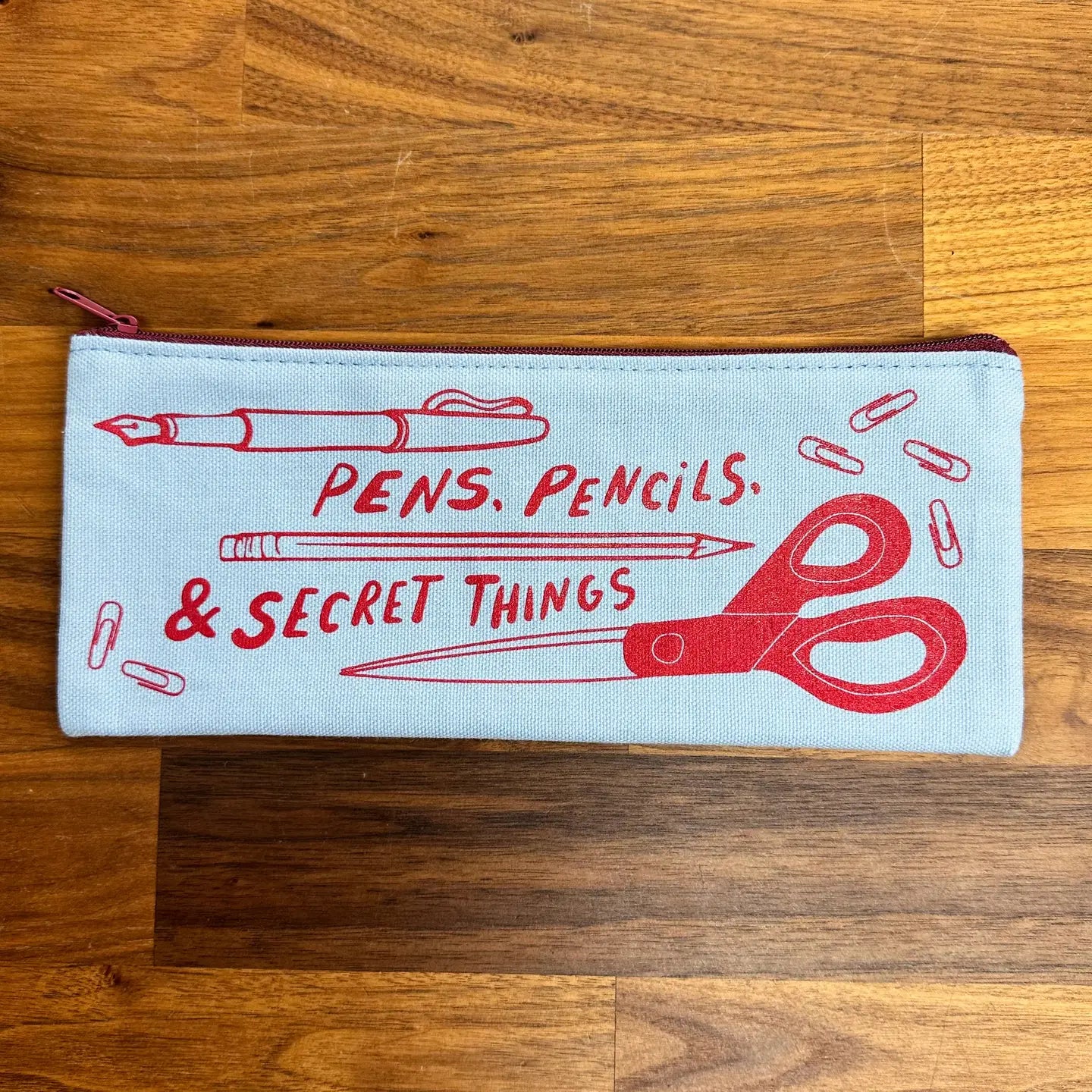 Light blue canvas pencil case with red illustrations and text