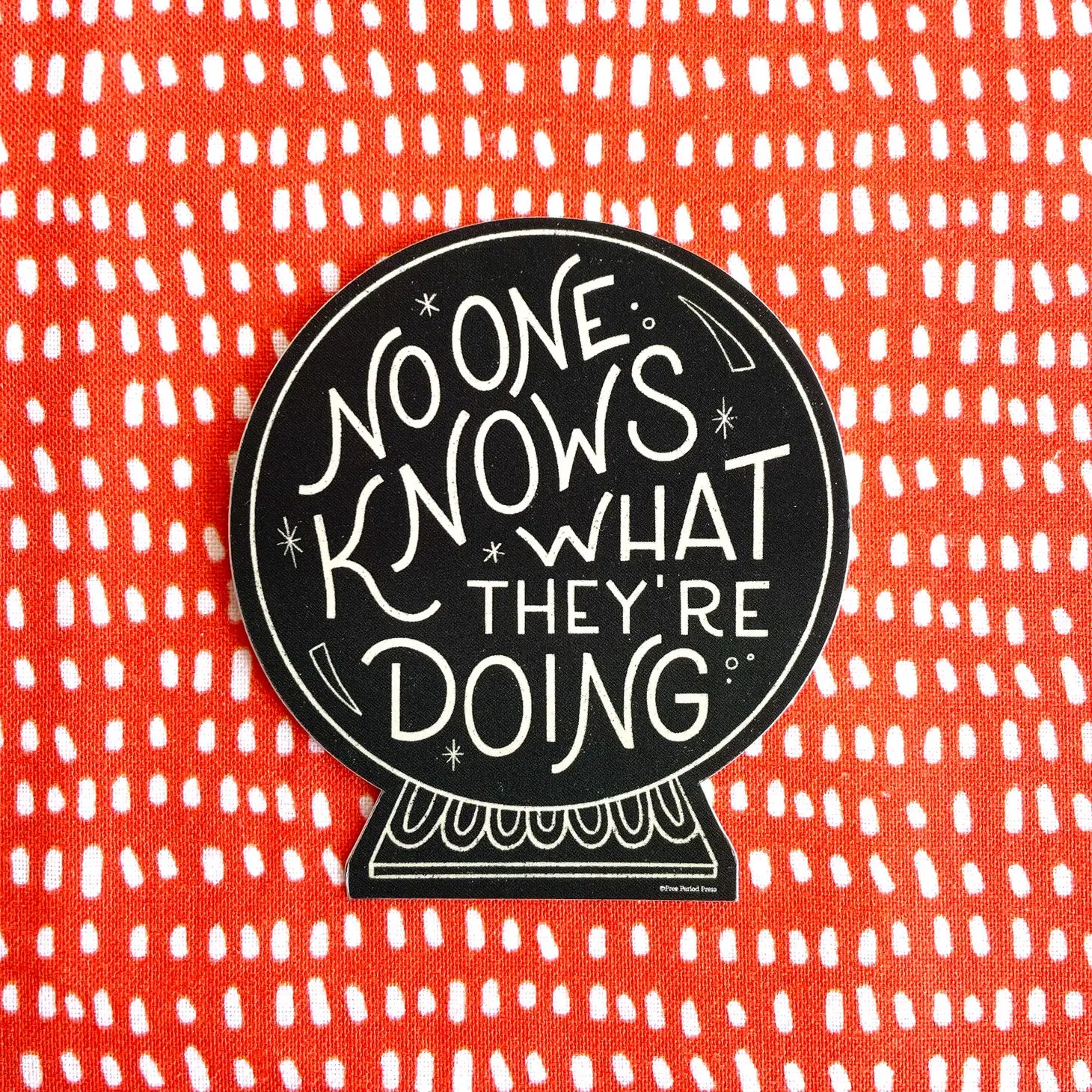Black sticker on orange and white dotted background. Sticker is shaped like a crystal ball. White text on sticker reads "no one knows what they're doing"