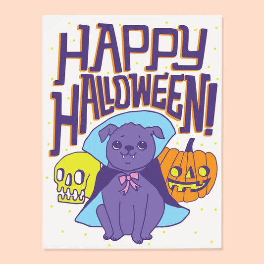 White card with an illustration of a pug dressed as a vampire. Purple and orange text reads “happy Halloween!” 