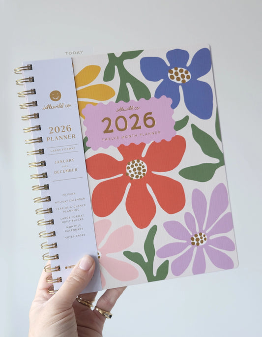 2026 planner with floral design held by a hand on a light gray background