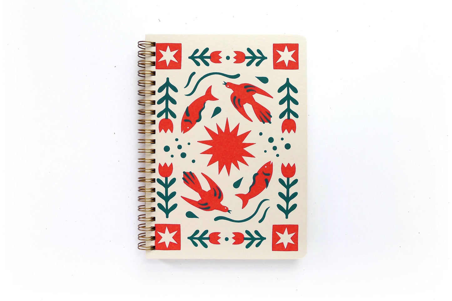 Front cover of a spiral notebook. White cover with red and green folk art pattern 