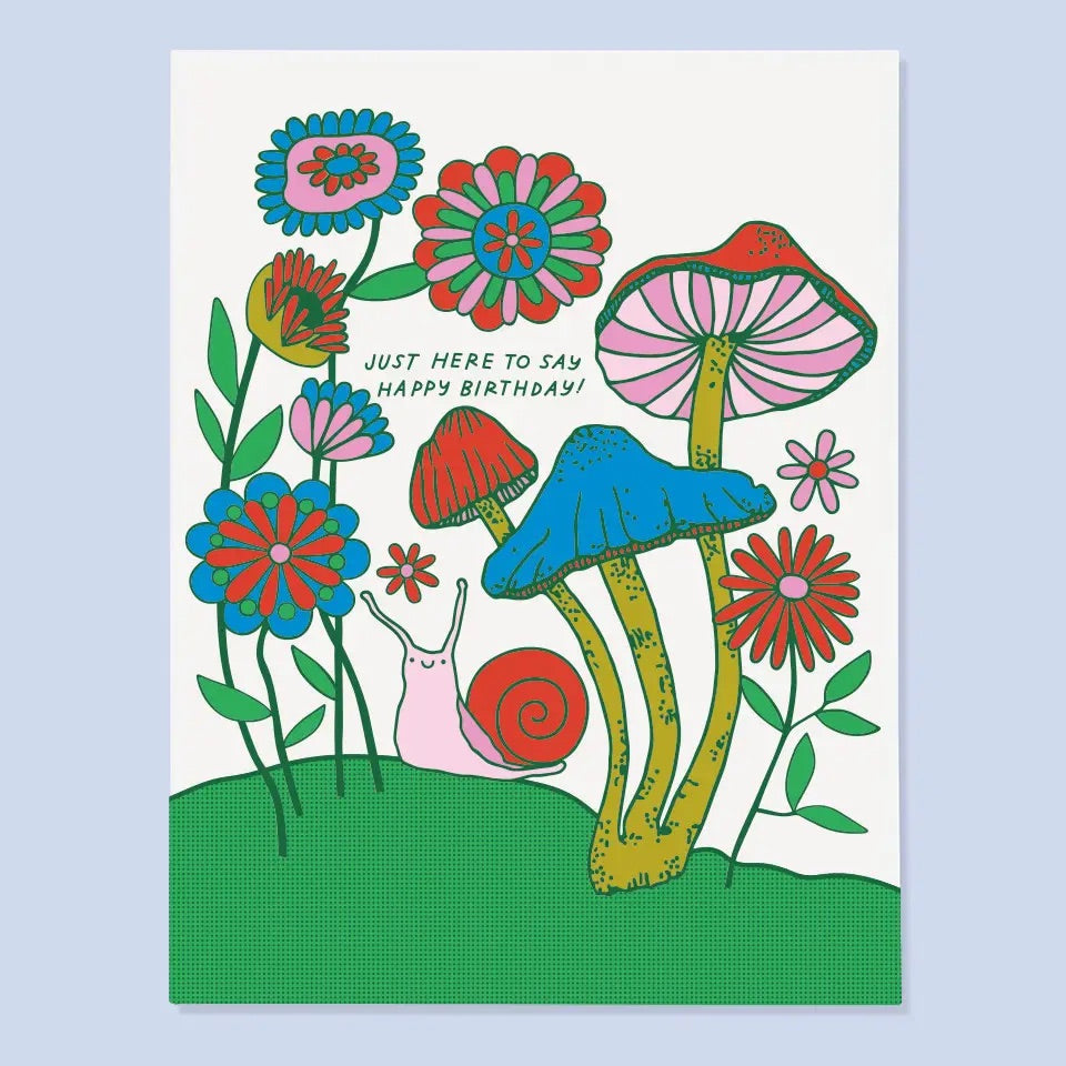 White card with red, blue, pink, and green illustration of mushrooms and a snail. "Just here to say happy birthday!" in green text. 