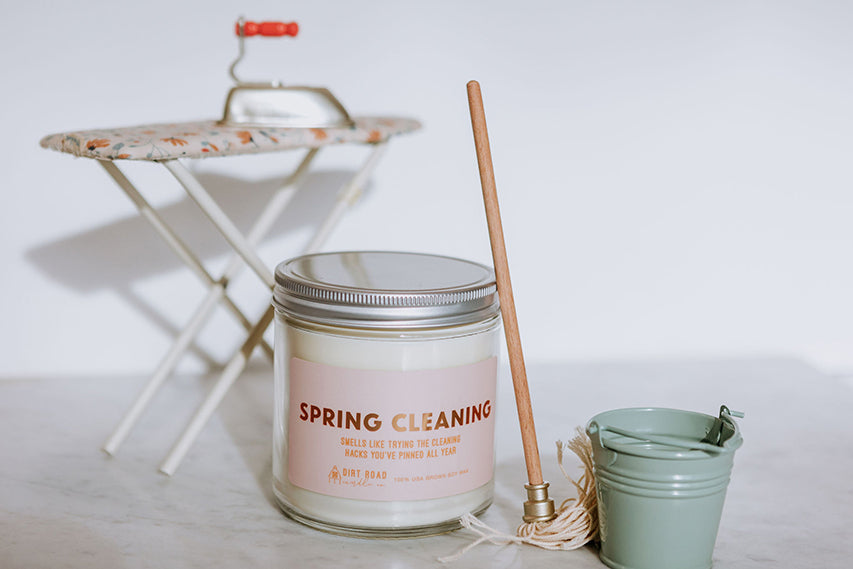 Clear jar filled with white candle. Pink label with text “spring cleaning”