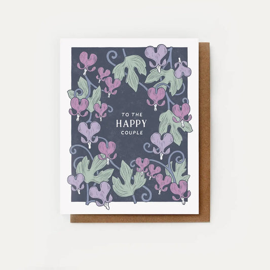 White card with navy background. Purple and green floral illustrations. White text reads “to the happy couple” 