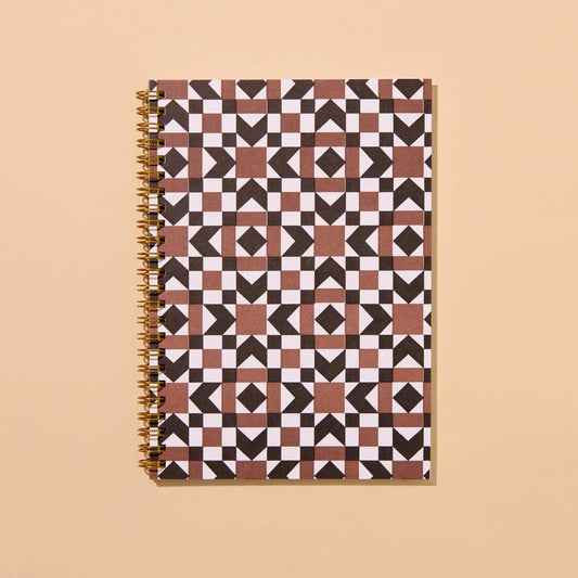 Front cover of a spiral notebook. Notebook is letterpress printed with a brown and black autumnal quilt print. 