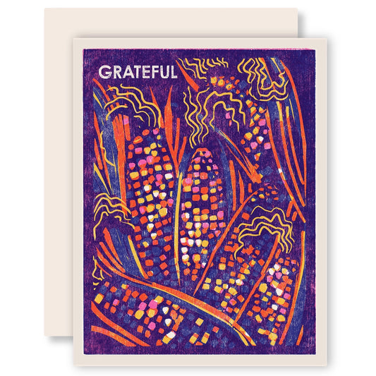 White greeting card with full color purple background. Multicolor corn illustration. White text "grateful" 