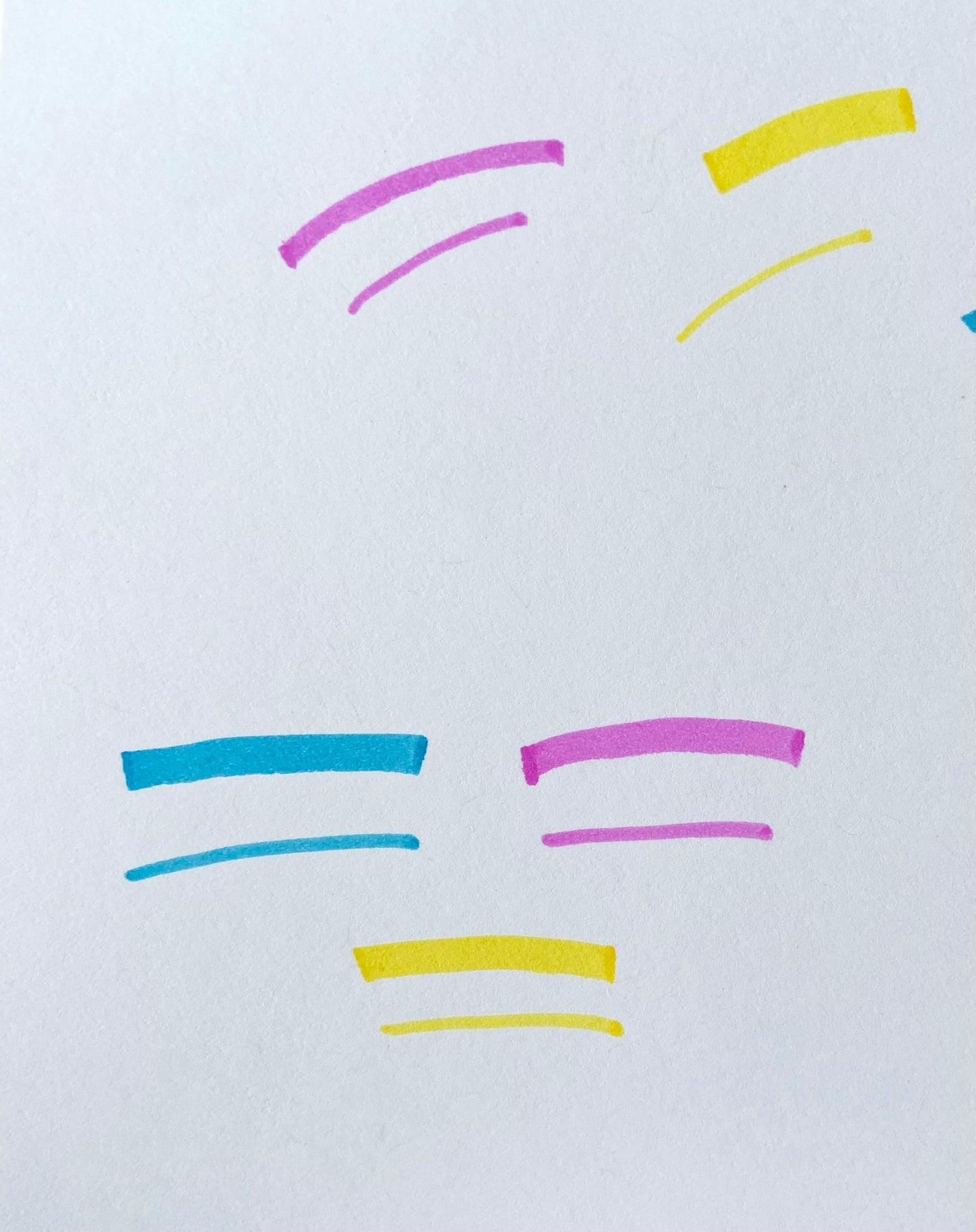 Pink, blue, and yellow highlighter lines on a white piece of paper. 