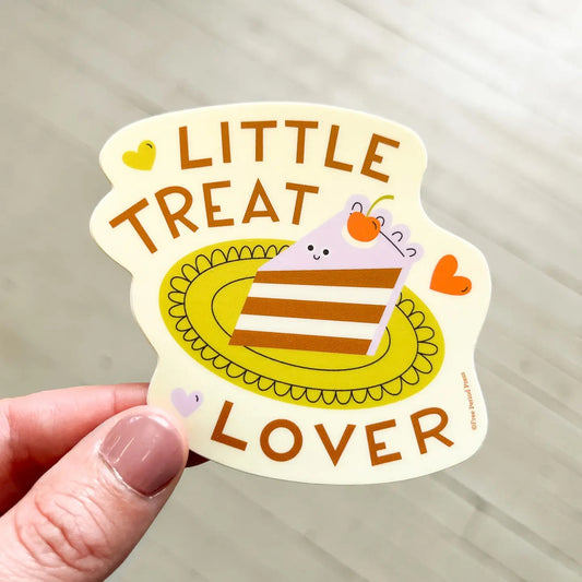 Die-cut sticker with an illustration of a slice of cake. Brown text "little text lover" 