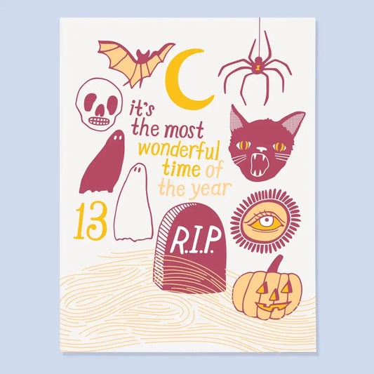 White card with red and orange spooky illustrations. Illustrations include ghosts, pumpkins, black cats, and a headstone. Red and yellow text reads “it’s the most wonderful time of the year.”