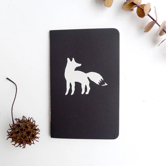 Front view of small black notebook. White fox print on front cover. 