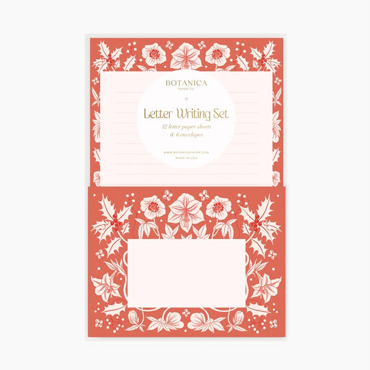 Front view of letter writing set. Lined pale pink paper with a red and white floral border. Red envelope with red and white floral border. 