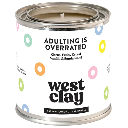 Tin candle with white label and colorful fruity cereal. Black text “adulting is overrated” 