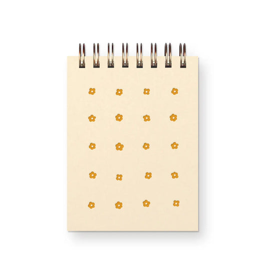 Front cover of top-spiral notebook. Cream color with yellow flower pattern. 