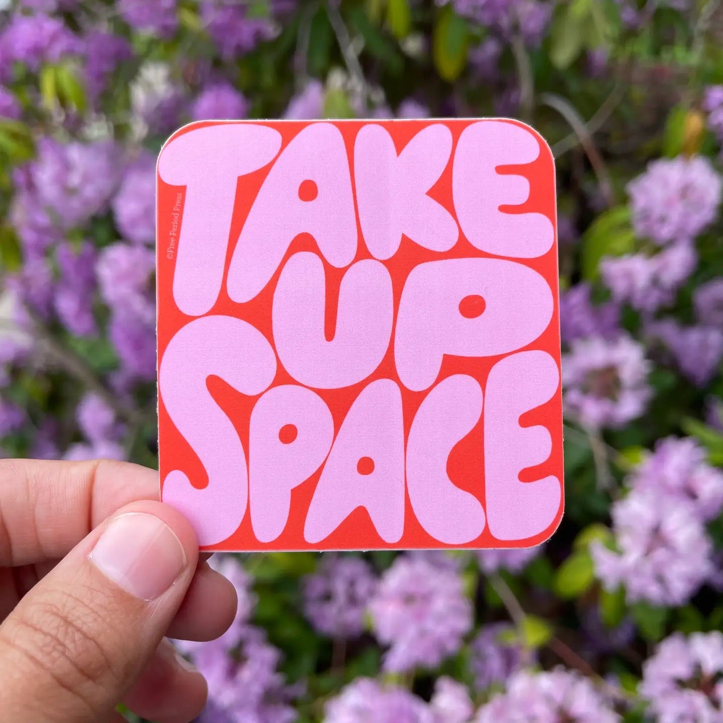 Square-shaped sticker with red background. Pink bubble text "take up space" 