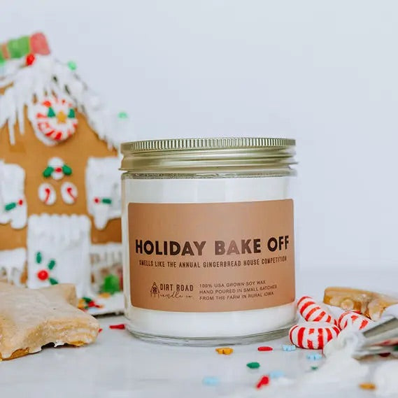 Clear jar filled with white candle. Brown label with darker brown text “holiday bake off” 