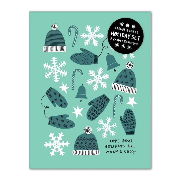 White card with full color mint background. Green and white illustrations of mittens and hats. Black text “hope your holidays are warm & cozy”