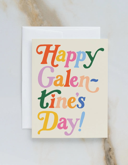 White greeting card with full color cream background. Multicolor text reads "happy galentine's day" 