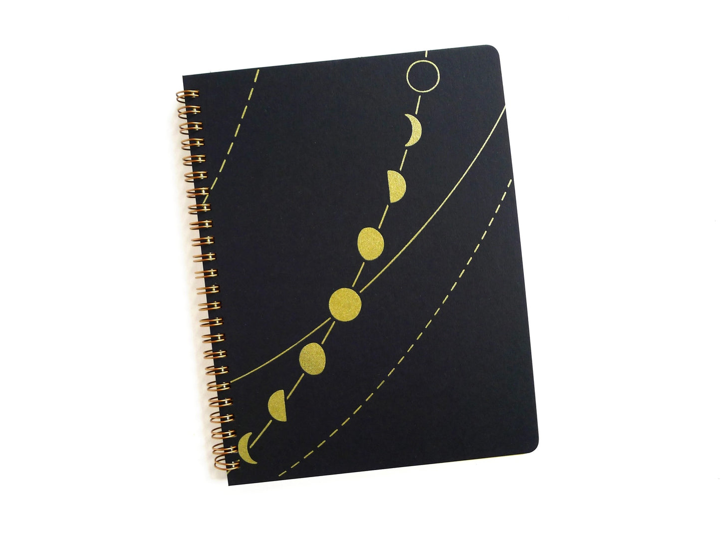 Front cover of a spiral notebook. Black cover with abstract gold moon phase pattern 