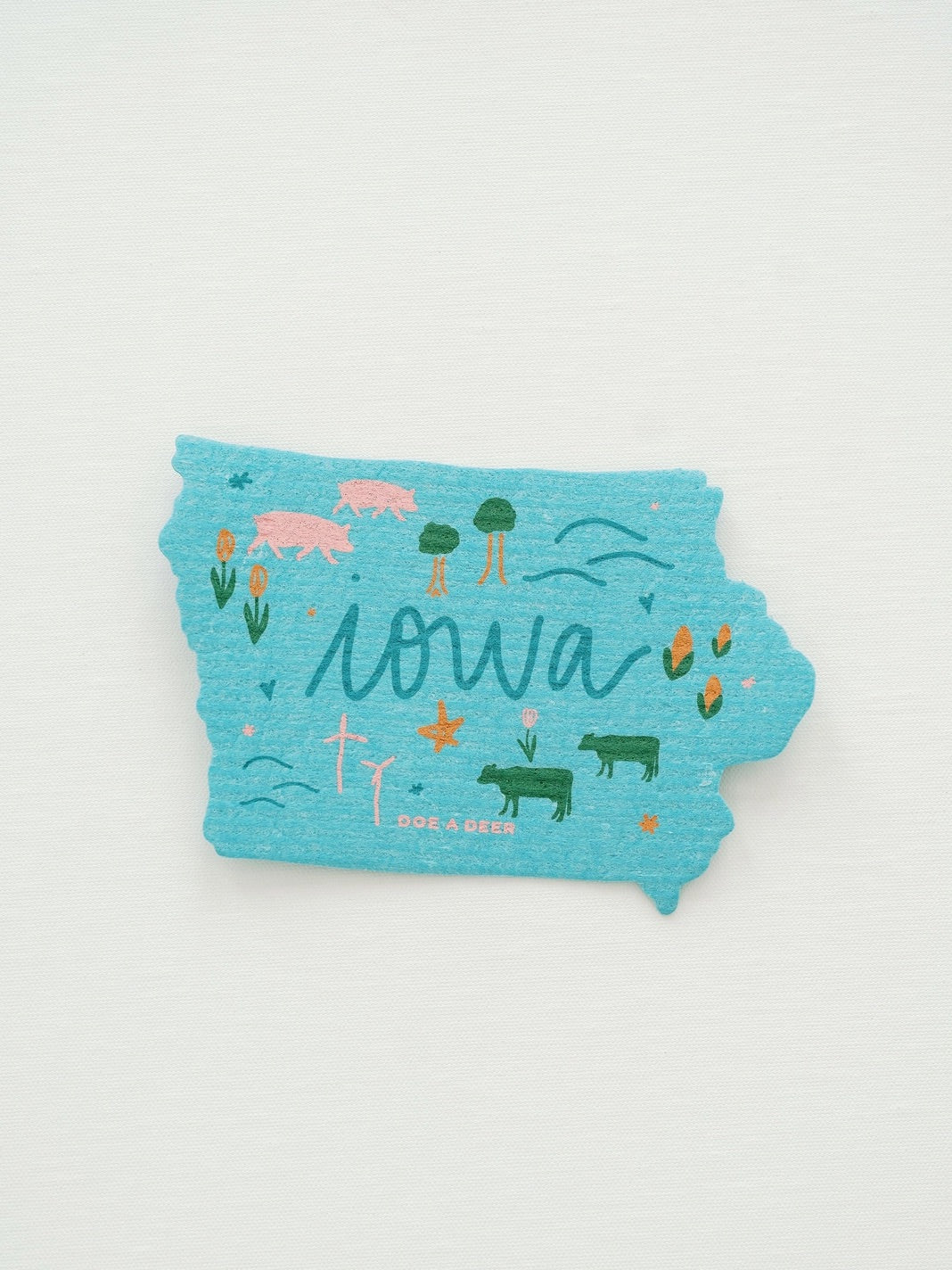 Blue Swedish dish cloth in the shape of Iowa. Colorful illustrations of flora and fauna. 