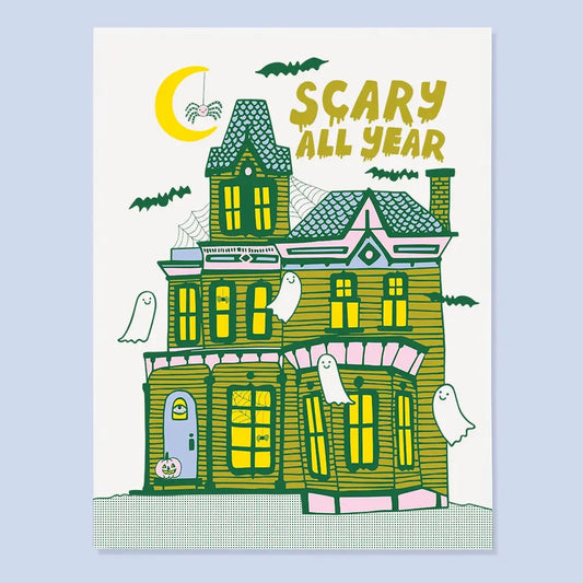 White card with an illustration of a haunted house with ghosts flying around. Mustard text reads “scary all year.” 