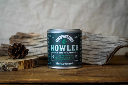 Candle with a dark grown label. Text on label reads "howler, white pine and eucalyptus" 