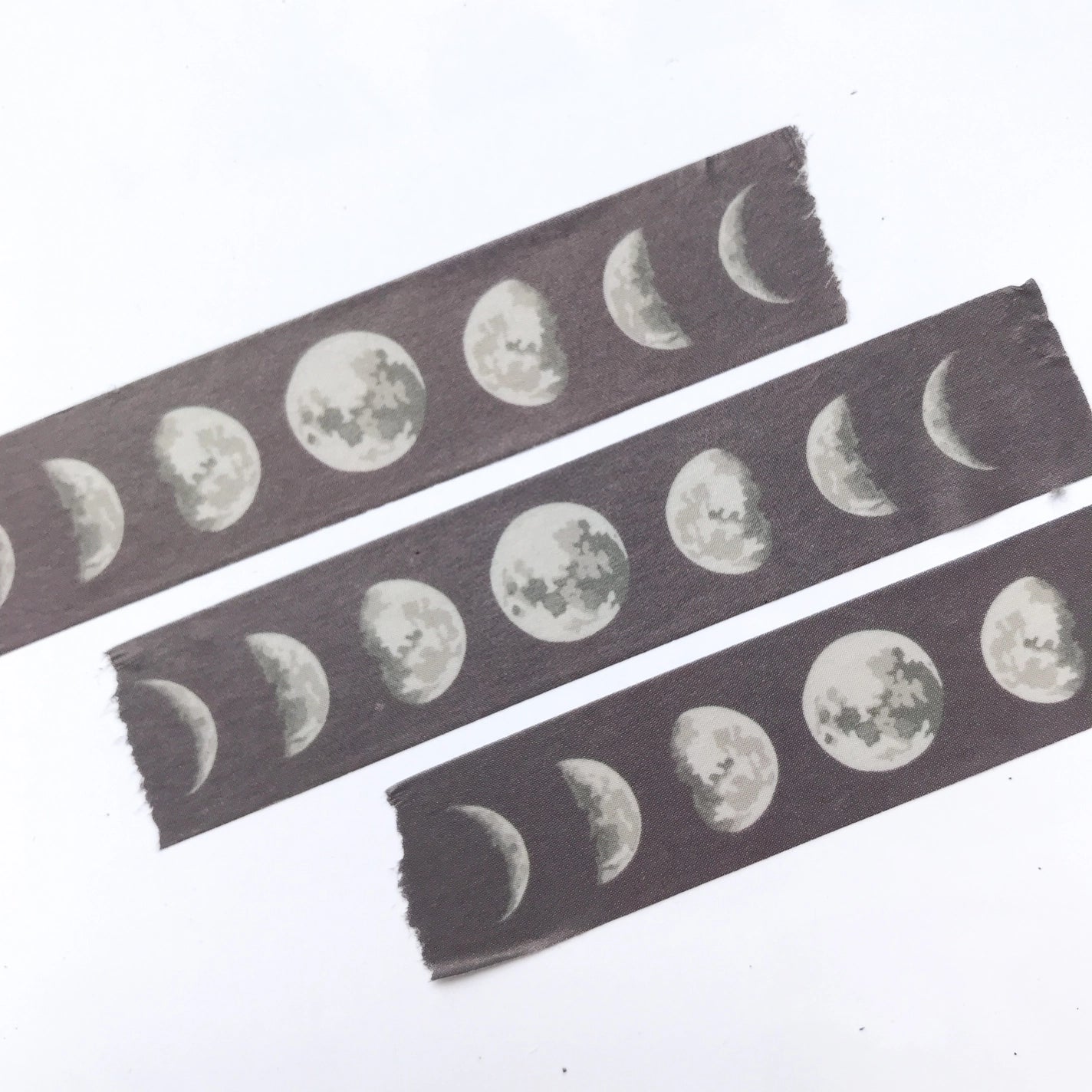 Three strips of Washi tape. Tape is black with white moon phase pattern.