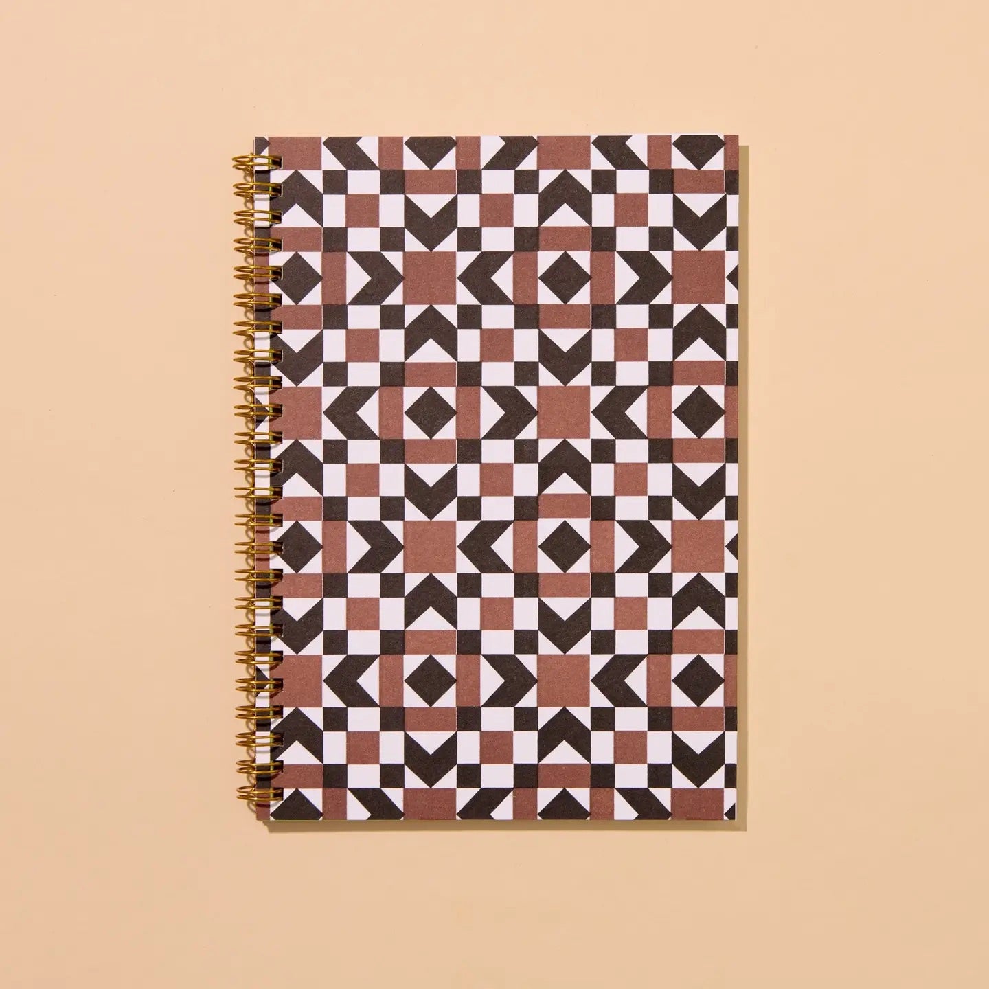 Front cover of a spiral notebook. Notebook is letterpress printed with a brown and black autumnal quilt print. 