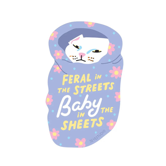 Die cut sticker featuring an illustration of a baby cat in a purple blanket with text 'Feral in the streets, Baby in the sheets' 