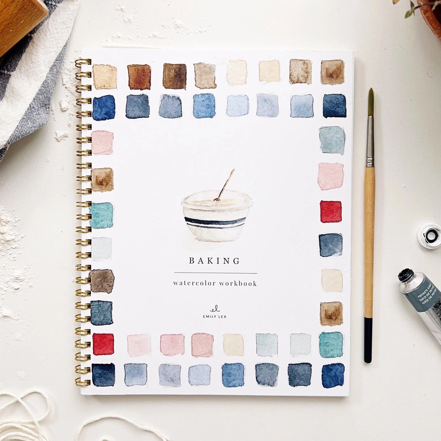 Spiral-bound watercolor workbook with white cover and a baking bowl painting. Black text reads "baking watercolor workbook." 