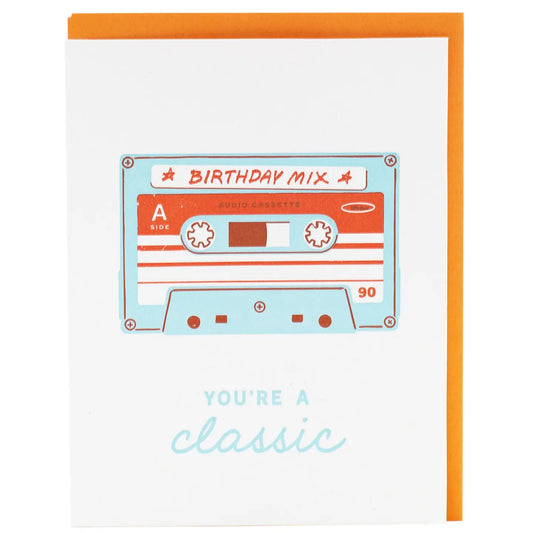 White greeting card with a picture of a cassette tape labeled “birthday mix.” Blue text, you’re a classic 
 
