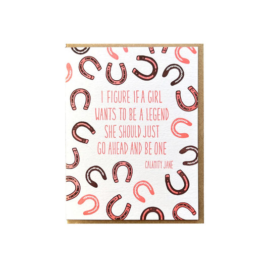 White greeting card with illustrations of red, pink, and black horseshoes. Pink text reads a quote by Calamity Jane: "I figure if a girl wants to be a legend she should just go ahead and be one." 