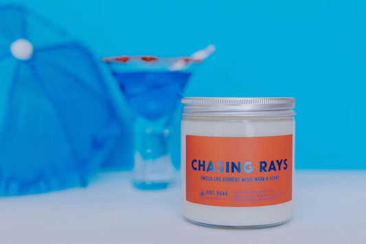 Clear jar with white candle. Orange label. Text on label: chasing rays