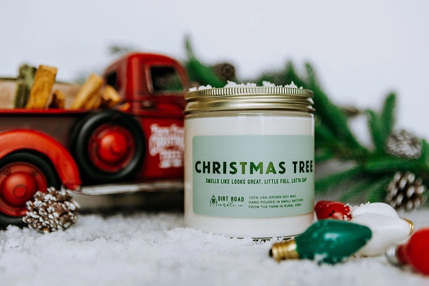 Clear jar filled with white candle. Green label with dark green text reads “Christmas tree”