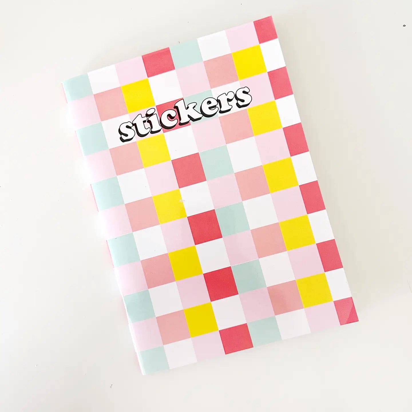 Front cover of a sticker book. Multicolor checkered pattern. White bubble letters: stickers 