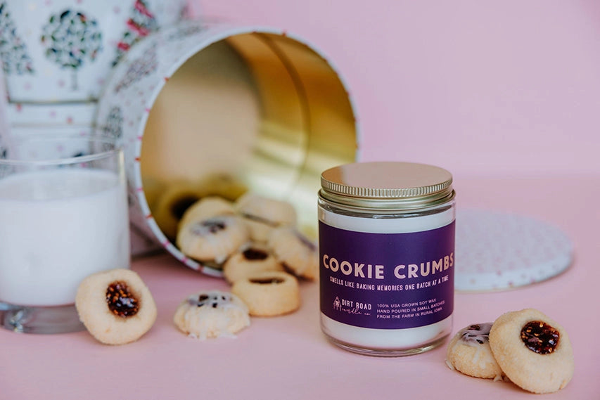 Jar of 'Cookie Crumbs' candle with cookies and a glass of milk on a pink background