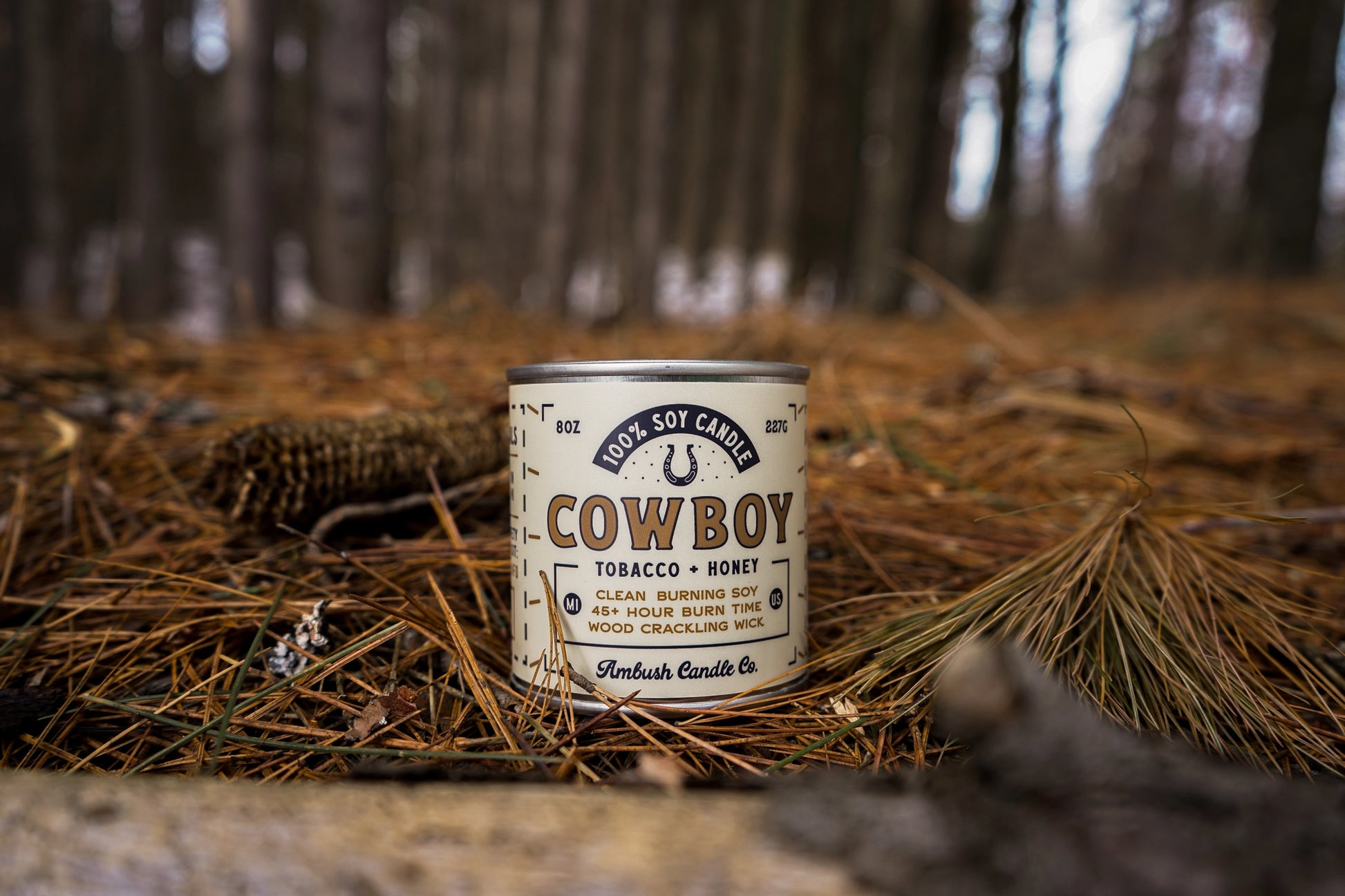 Cowboy candle canister on a forest floor with blurred trees in the background