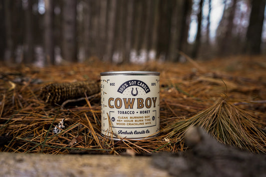 Cowboy candle canister on a forest floor with blurred trees in the background