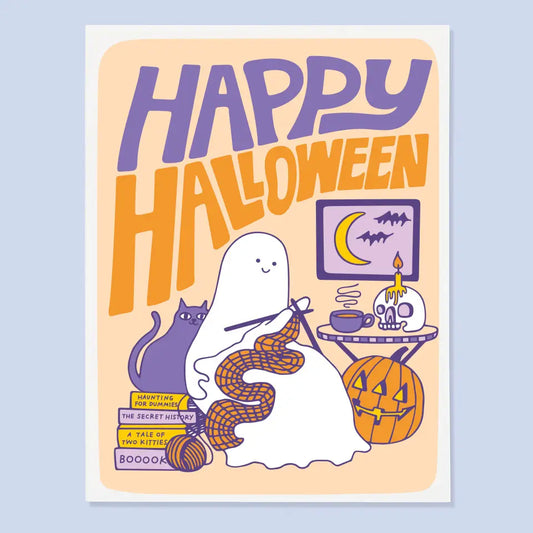 White greeting card with an orange, purple, and white illustration of a ghost knitting near a cat and pumpkin. Text: happy Halloween 