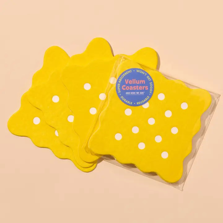 Yellow cracker shaped coasters in a clear package on a beige background