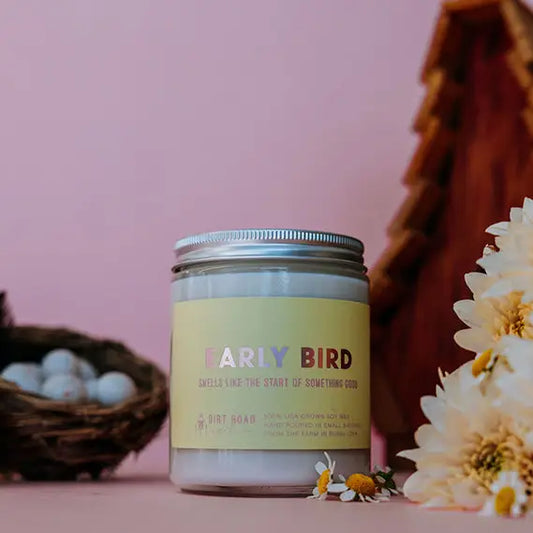 Candle jar labeled 'Early Bird' with flowers and a pink background