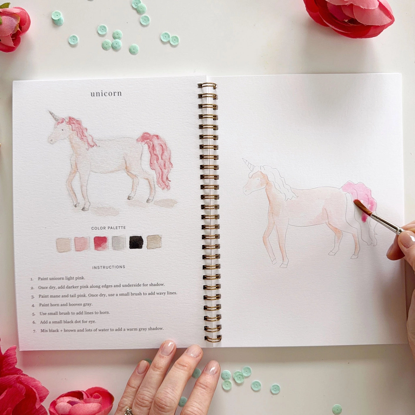 Open book with person painting a unicorn illustration