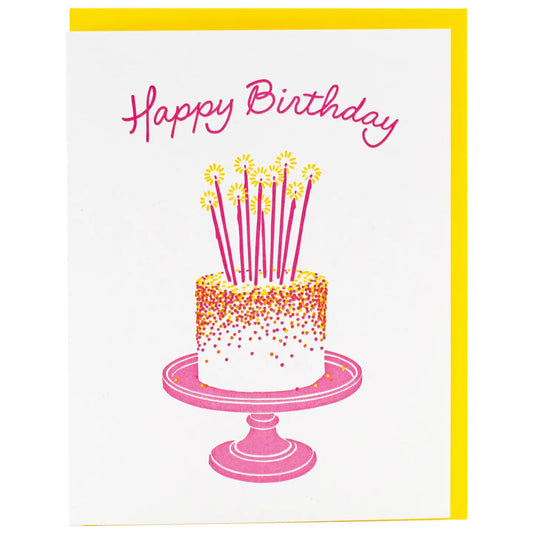 White greeting card with a pink, yellow, and white cake illustration. Pink text: happy birthday